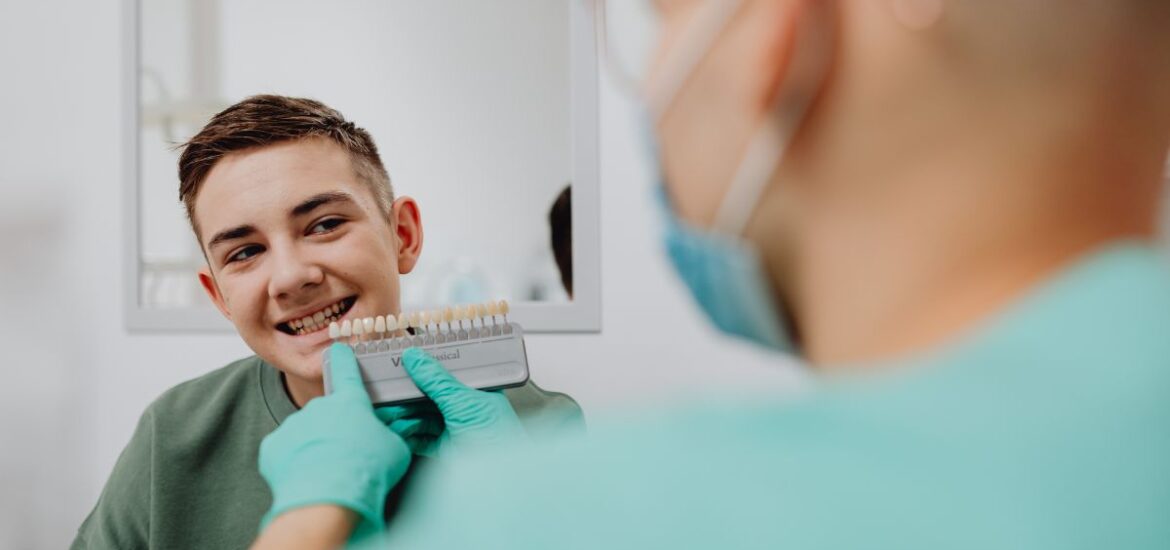 Man brushing teeth in bathroom mirror wearing green shirt and latex gloves.