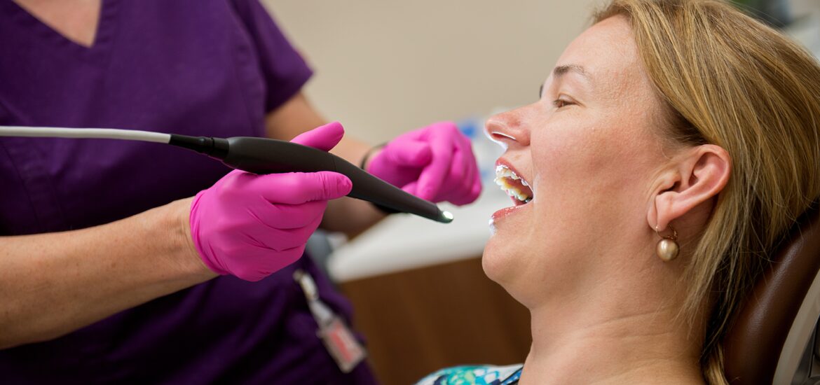 Dentist in purple gloves examining patient's teeth during dental checkup at clinic.